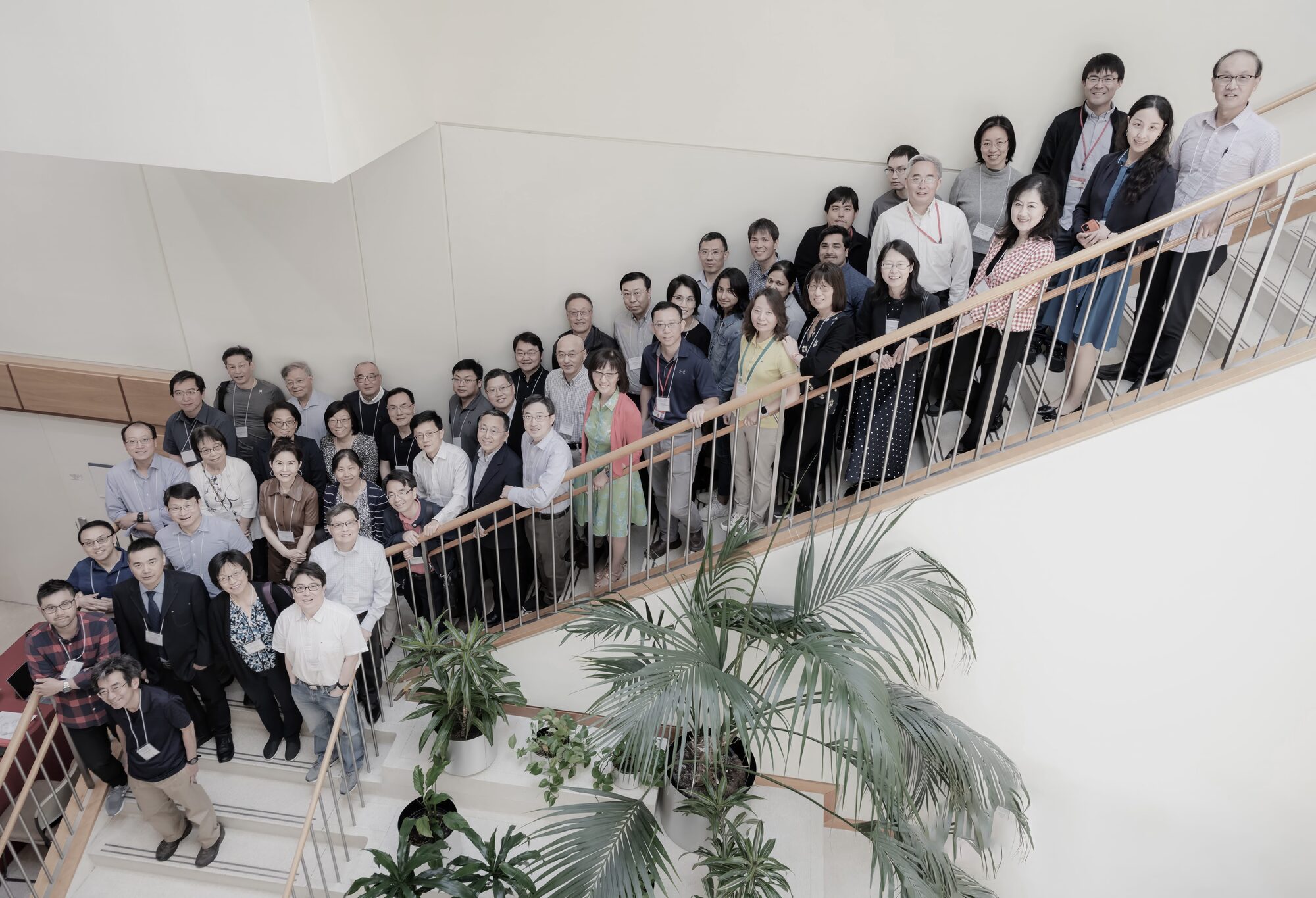 Investigators with name badges stand along a staircase at a scientific meeting.